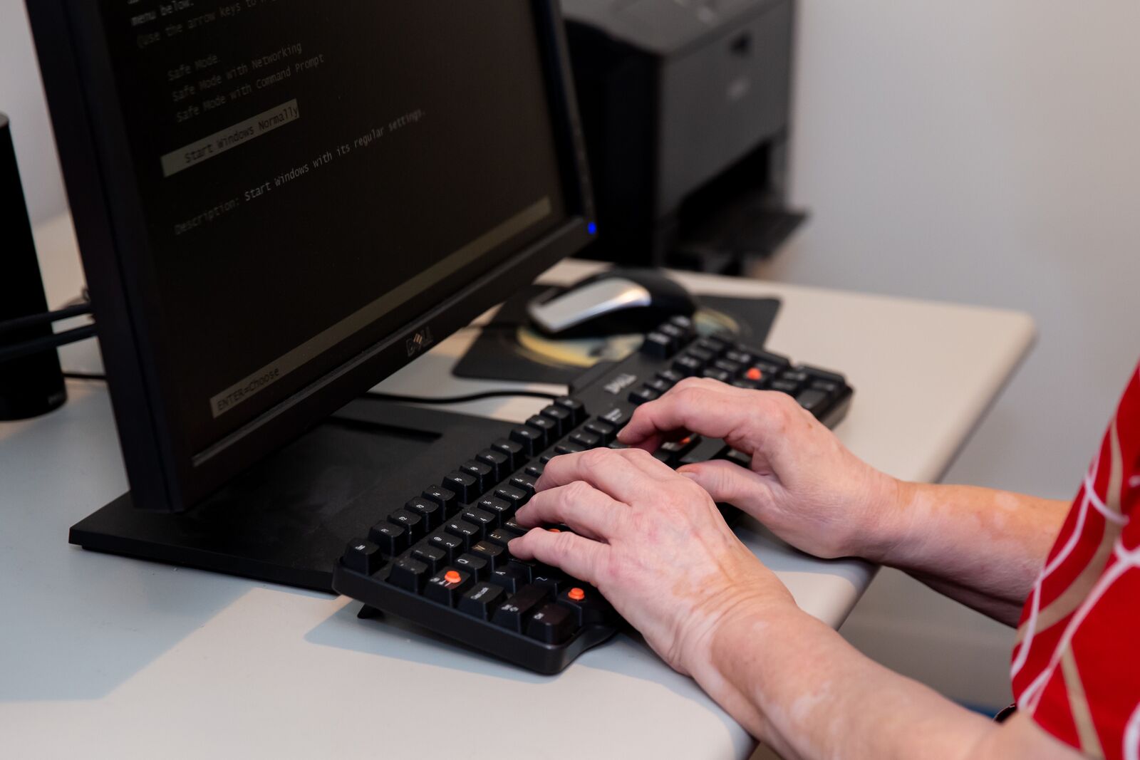 a person is typing on the keyboard of a desktop computer.