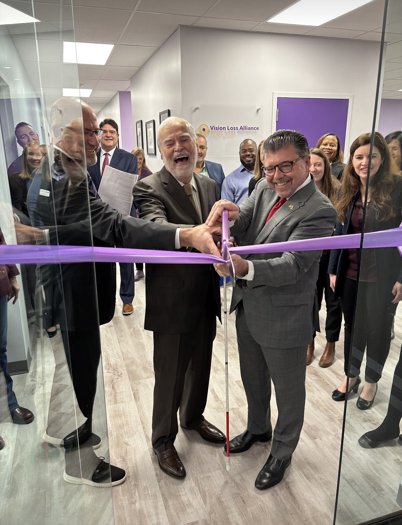 Carl Augusto, Bill Schuldt, and Senator Bucco cut purple ribbon at the door of VLANJ's new Morris Plains, NJ location.